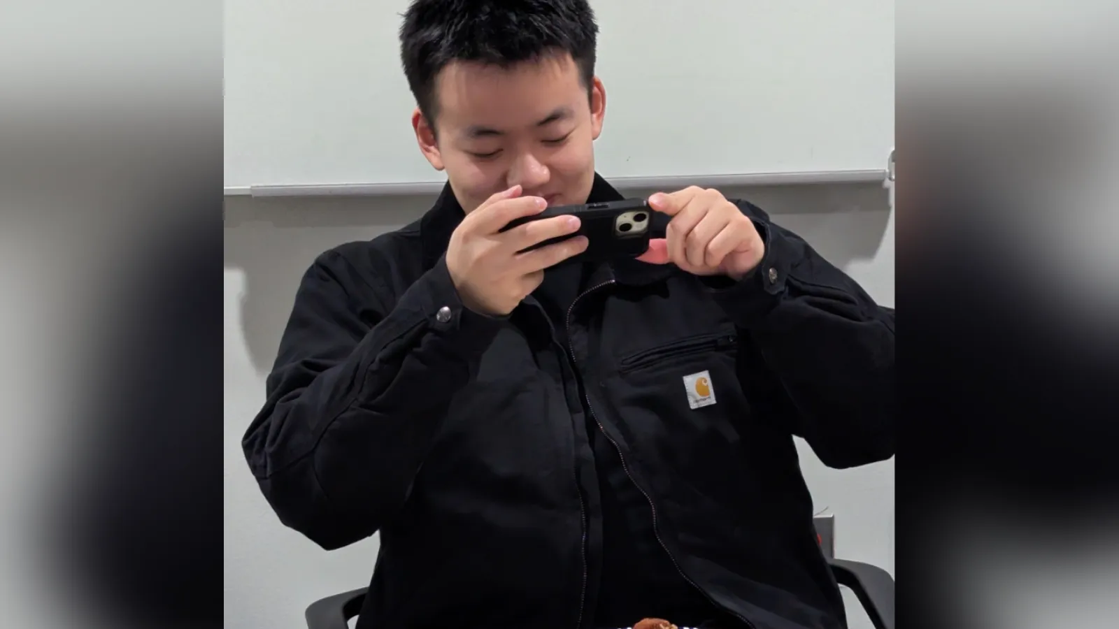Student in black jacket taking a photo of food sample