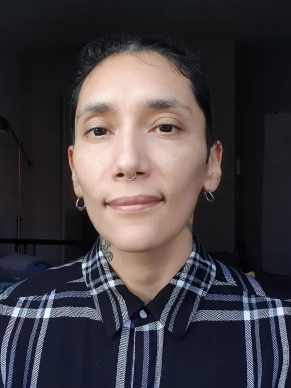 Portrait of queer brown person wearing a black and white button down.